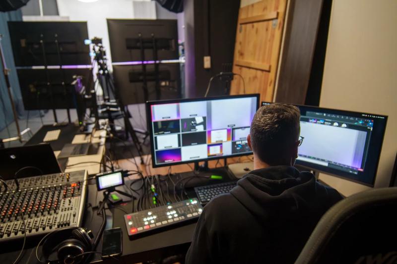 Rear view of adult Hispanic man TV editor working in television studio