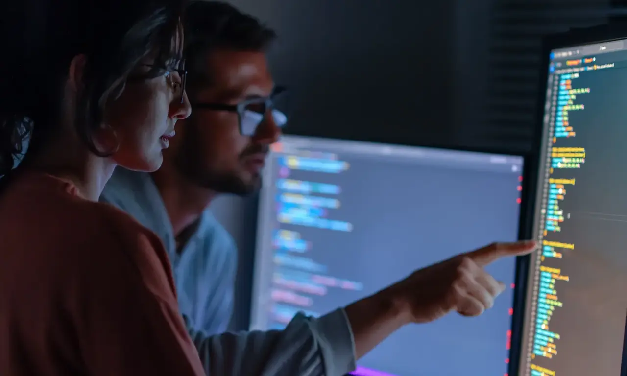 Security engineers reviewing code on monitors with NETGEAR Exium