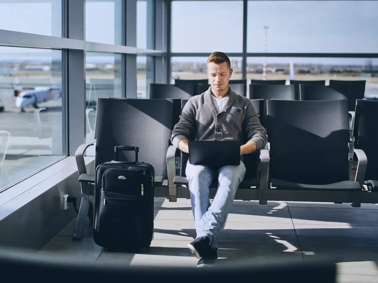 Traveler working on a laptop in an airport departure lounge